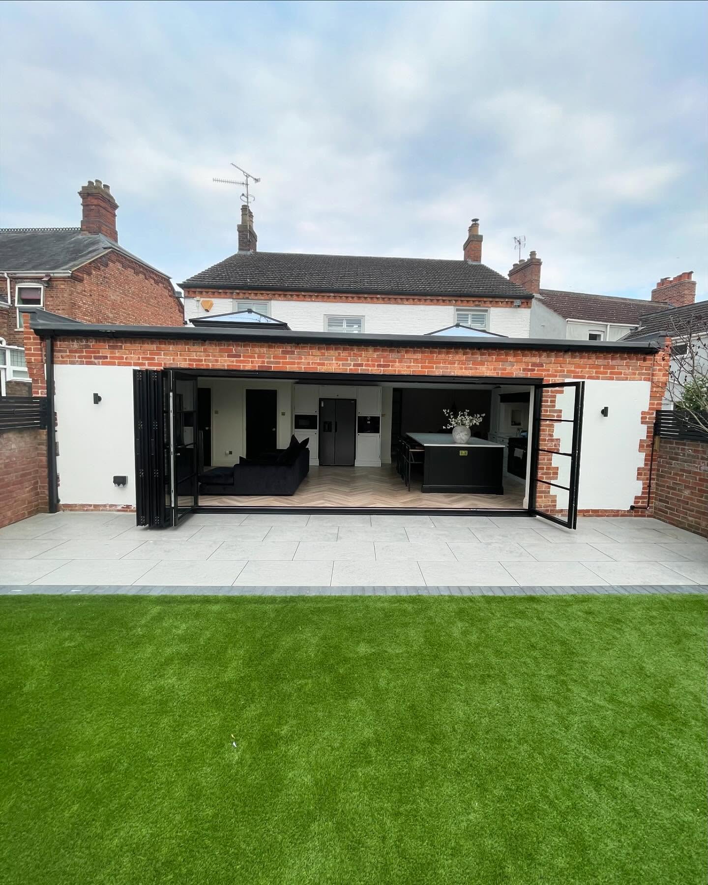 Brick extension with bifold doors fully open onto a porcelain terrace
