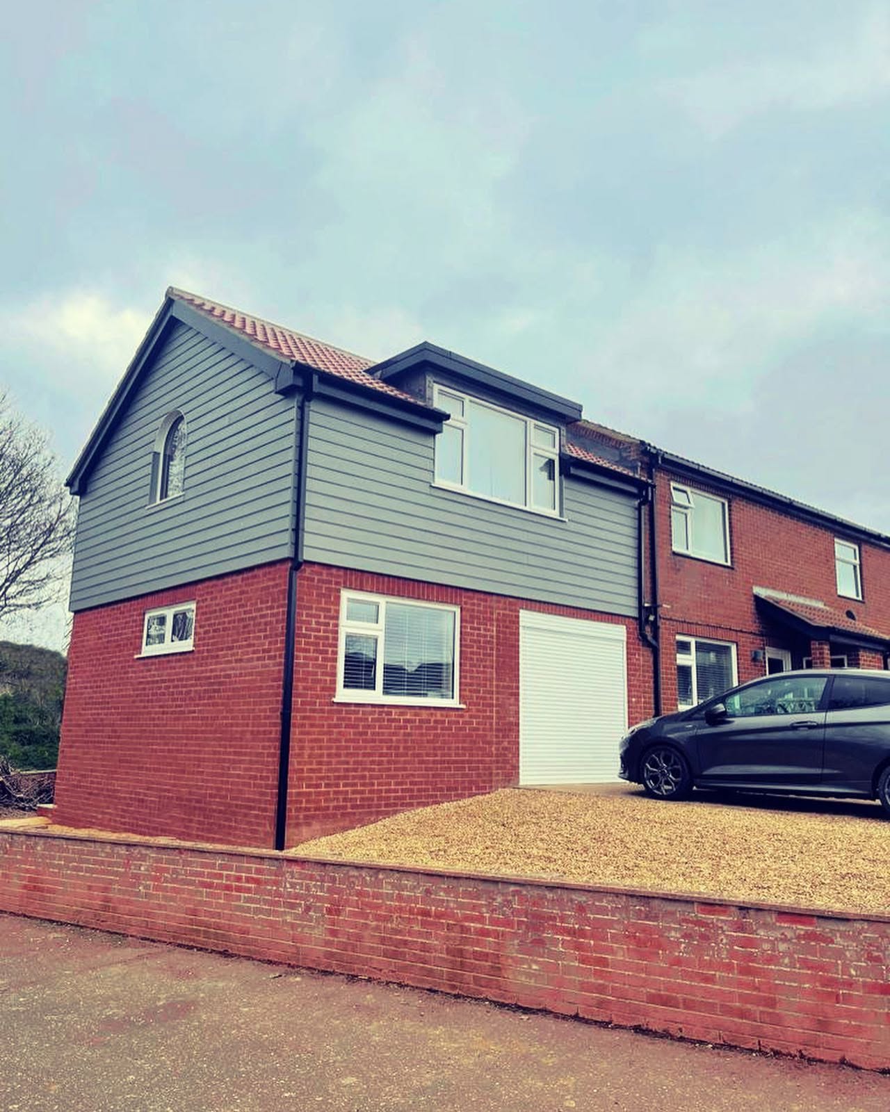 Two storey side extension in brick with grey feather-edge cladding