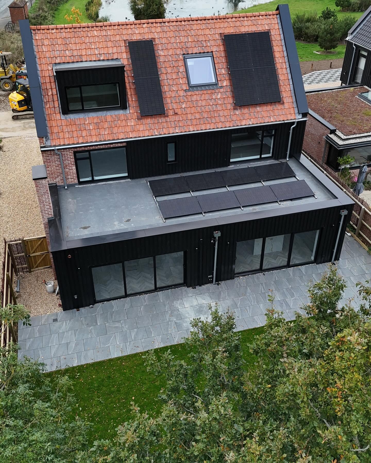 Aerial view of a black clad new build with solar array and porcelain terrace
