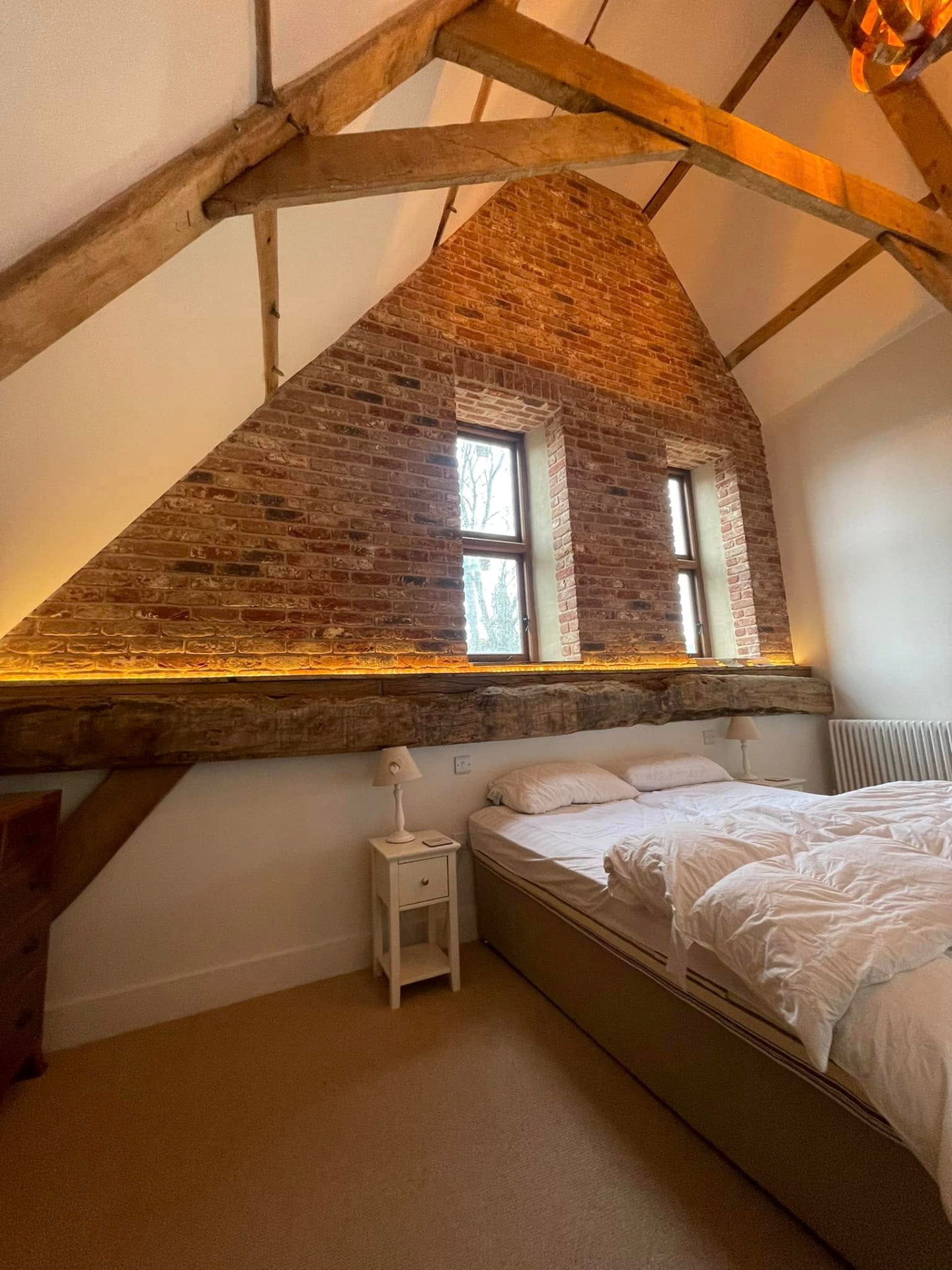 Barn conversion bedroom with exposed trusses and brick gable