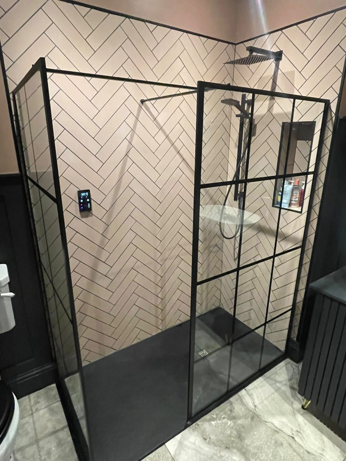 Walk-in shower with herringbone tiling and black framed screens