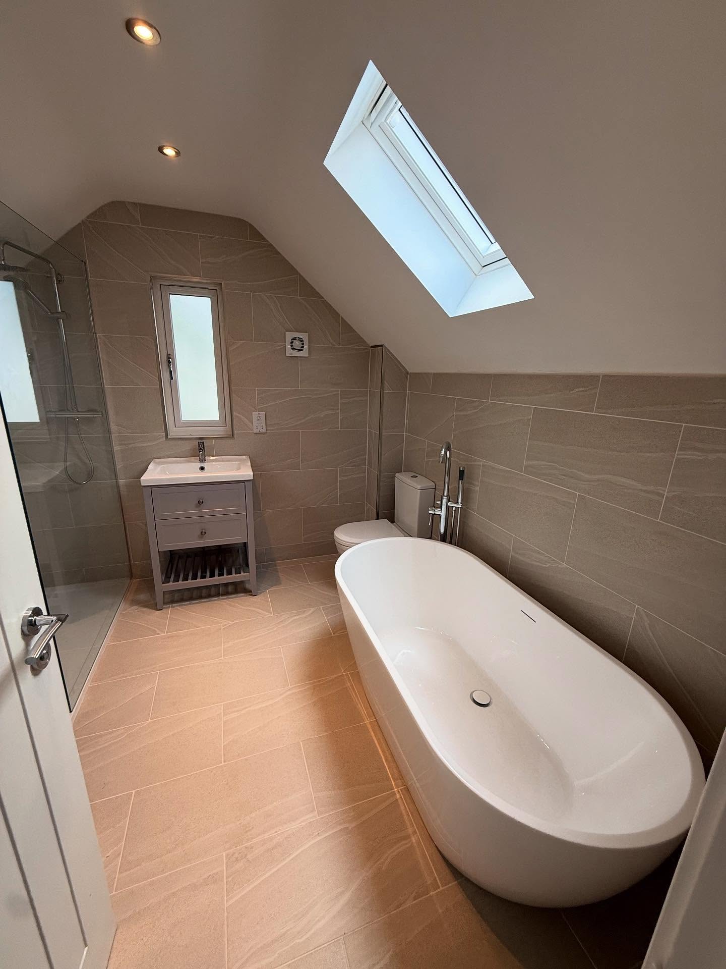 Loft bathroom with freestanding bath beneath a rooflight