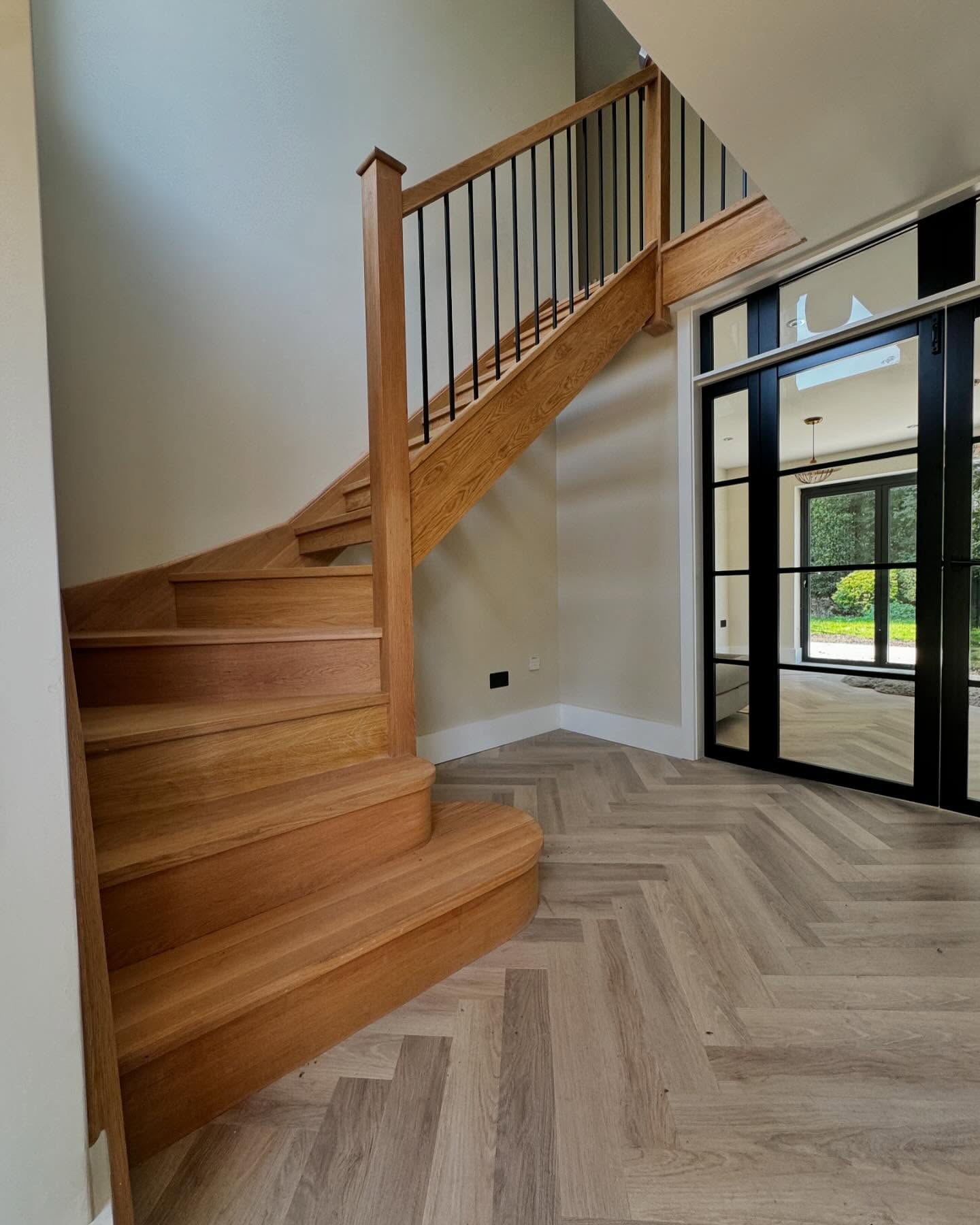 Bespoke oak staircase with curved bottom step and black spindles