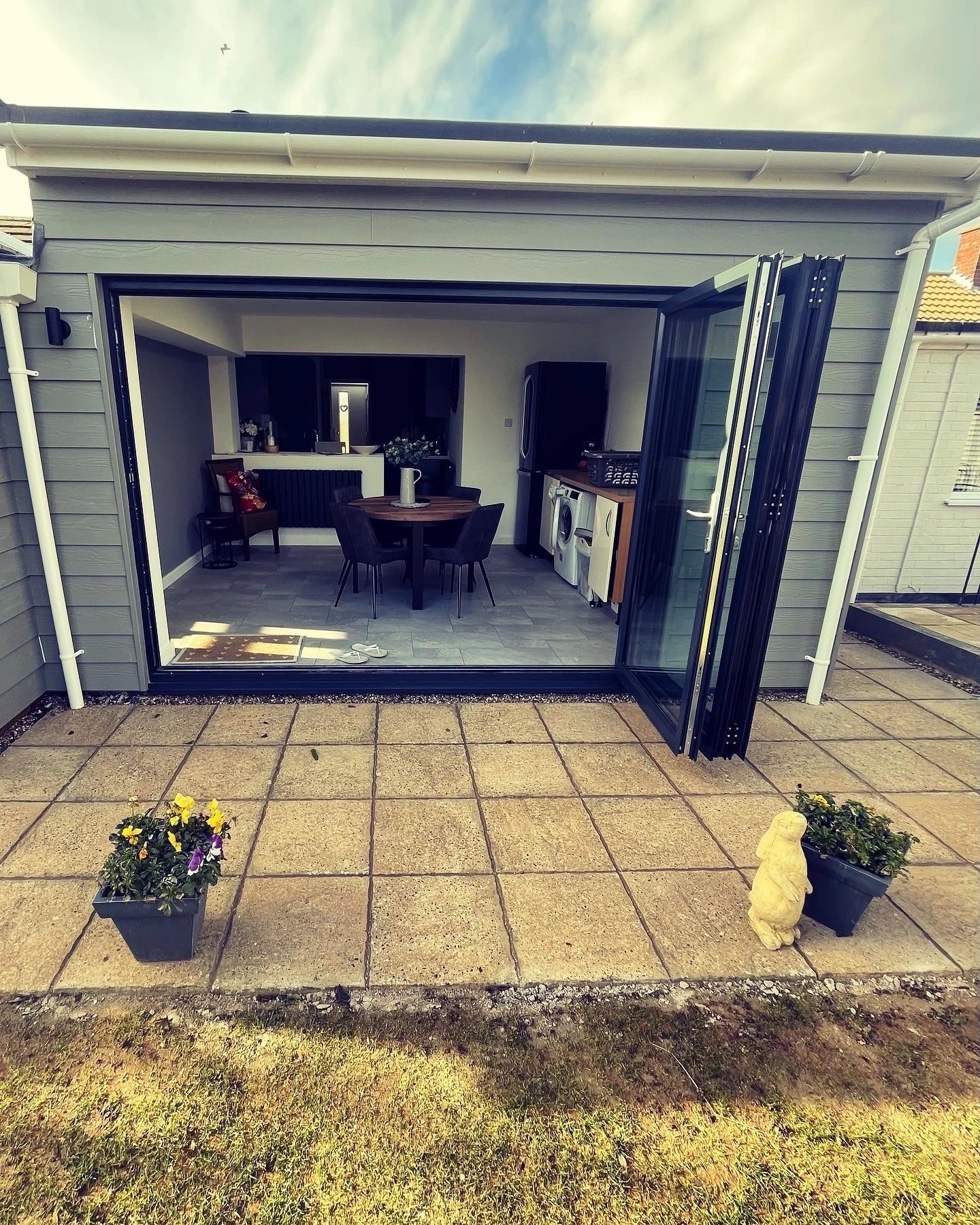 Grey clad single-storey extension in Old Hunstanton with anthracite bi-fold doors onto a paved terrace.