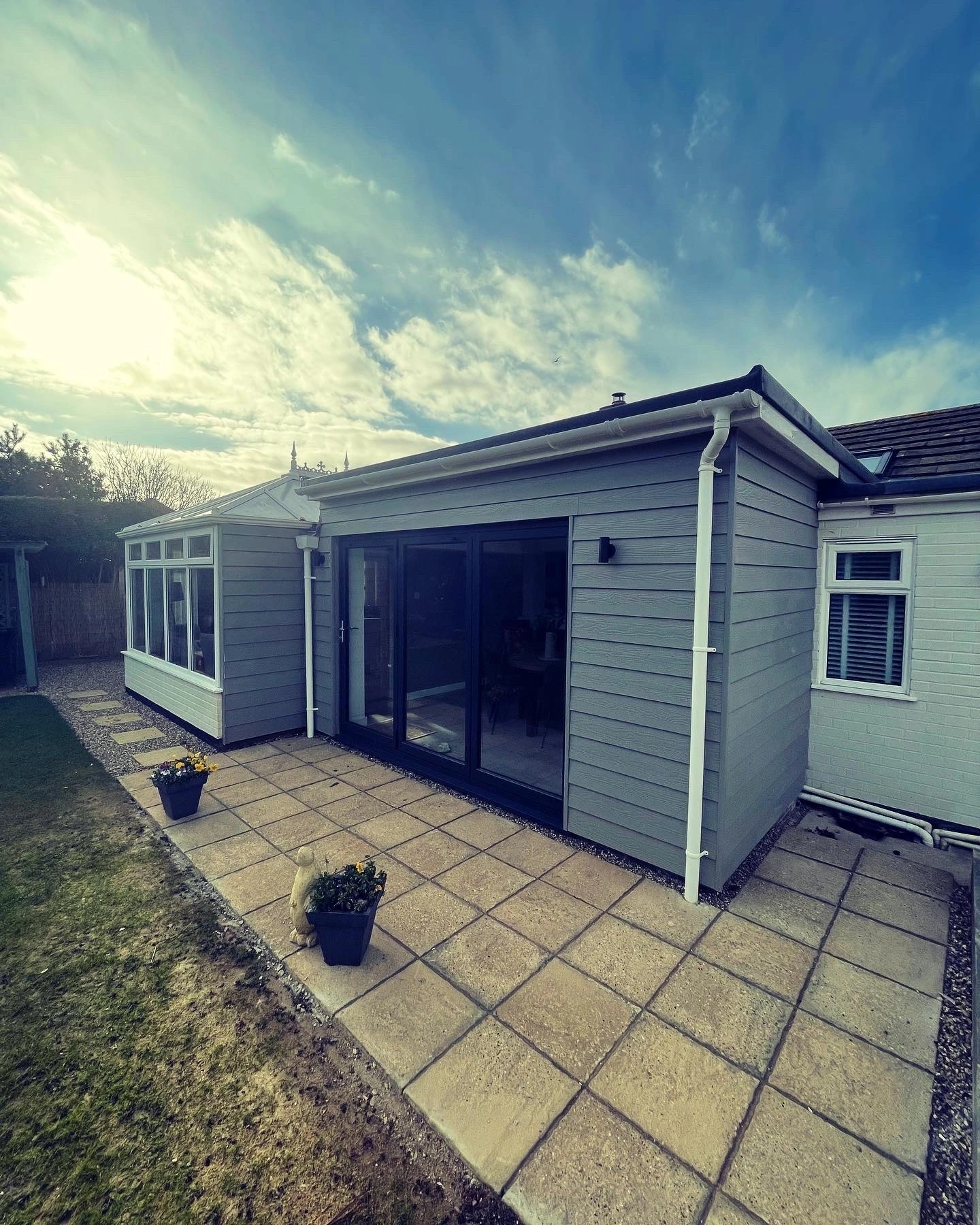 Grey clad single-storey extension in Old Hunstanton with anthracite bi-fold doors onto a paved terrace.