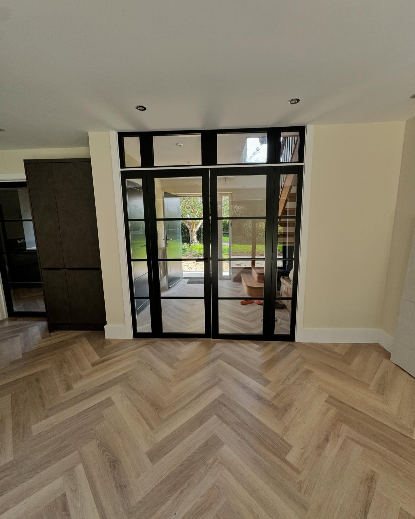 Steel framed internal doors and herringbone flooring in an open hallway