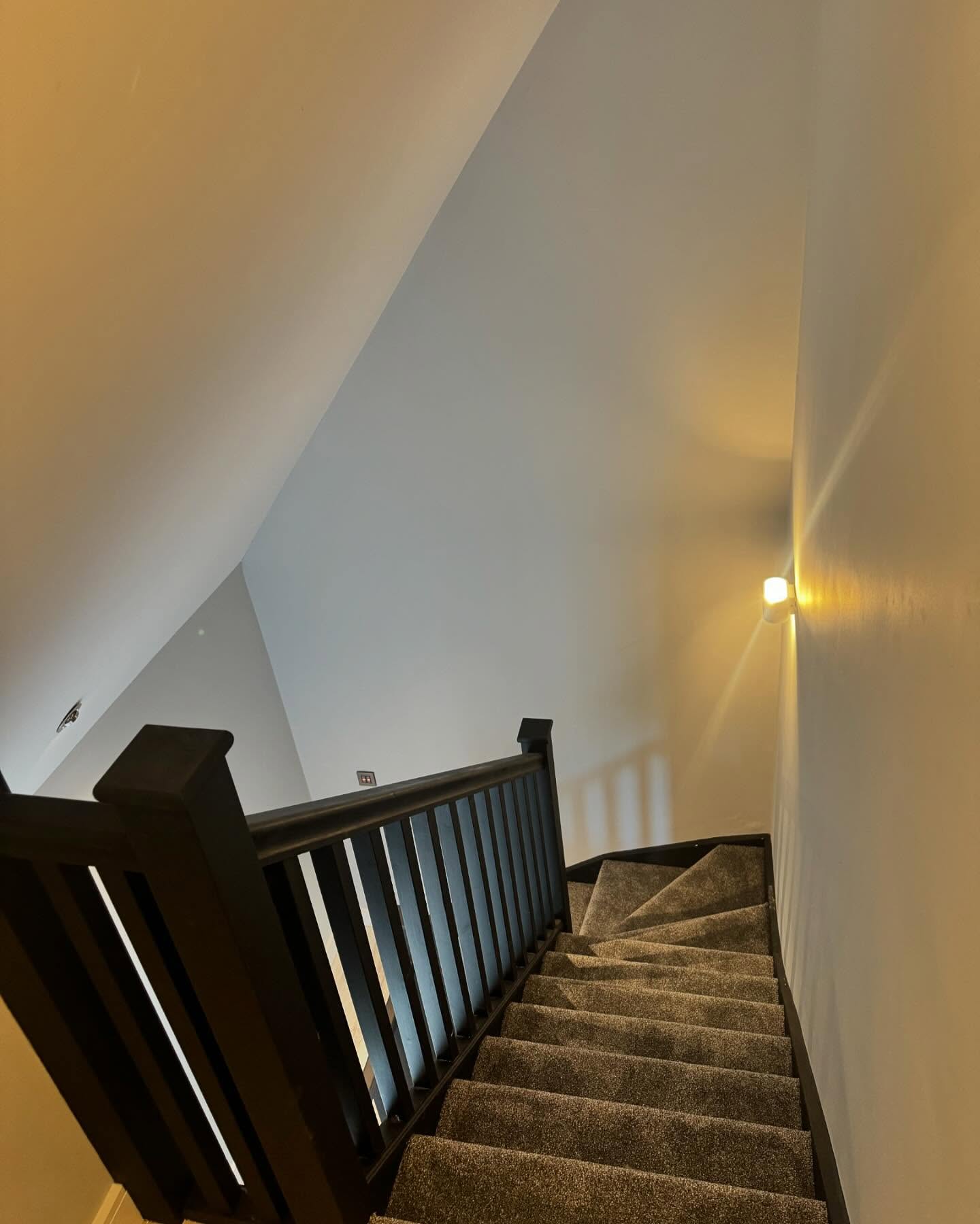 Stair to a converted loft with dark stained balustrade and coombed ceilings