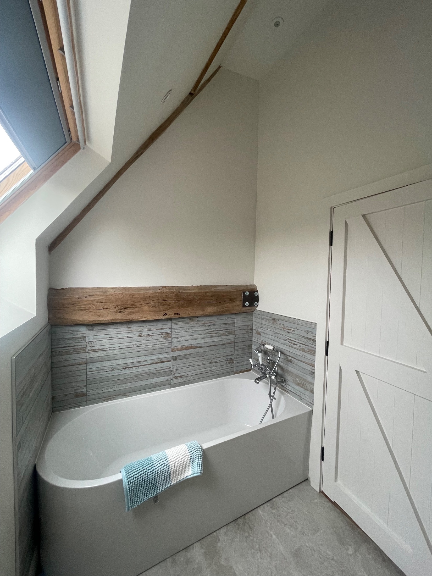 Barn conversion bedroom with exposed oak trusses and brick gable wall
