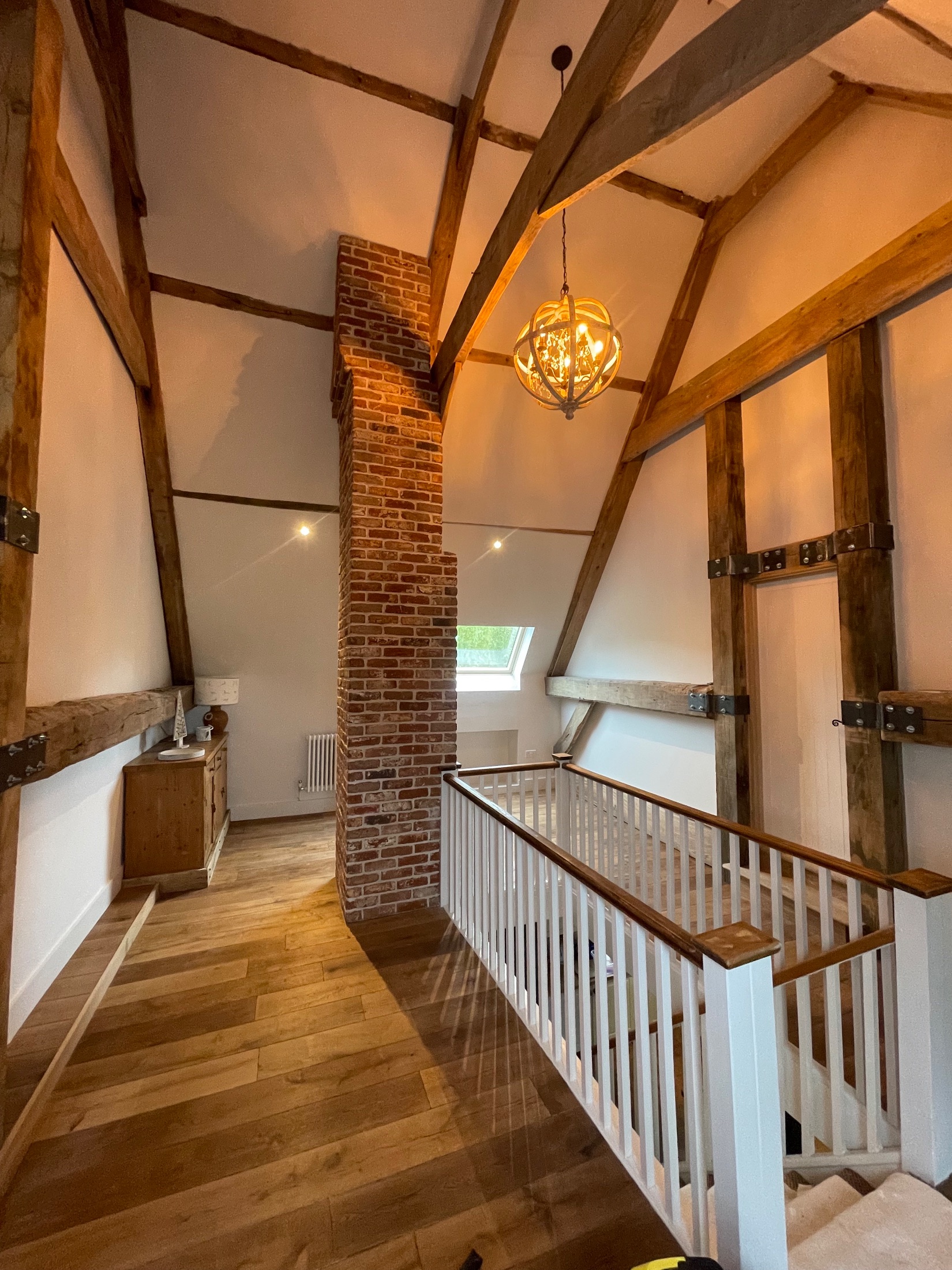 Barn conversion bedroom with exposed oak trusses and brick gable wall