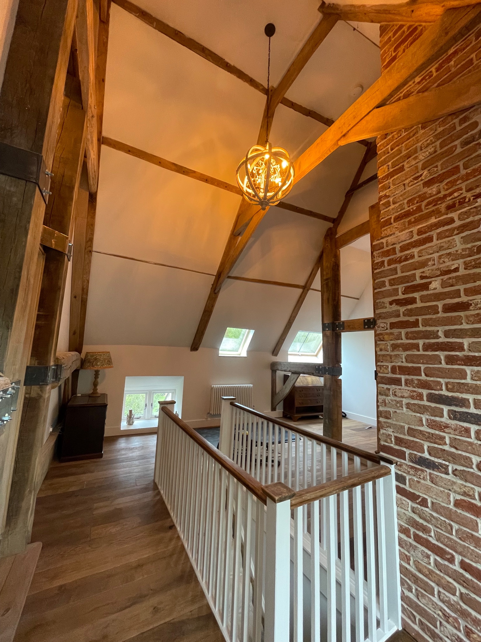 Barn conversion bedroom with exposed oak trusses and brick gable wall