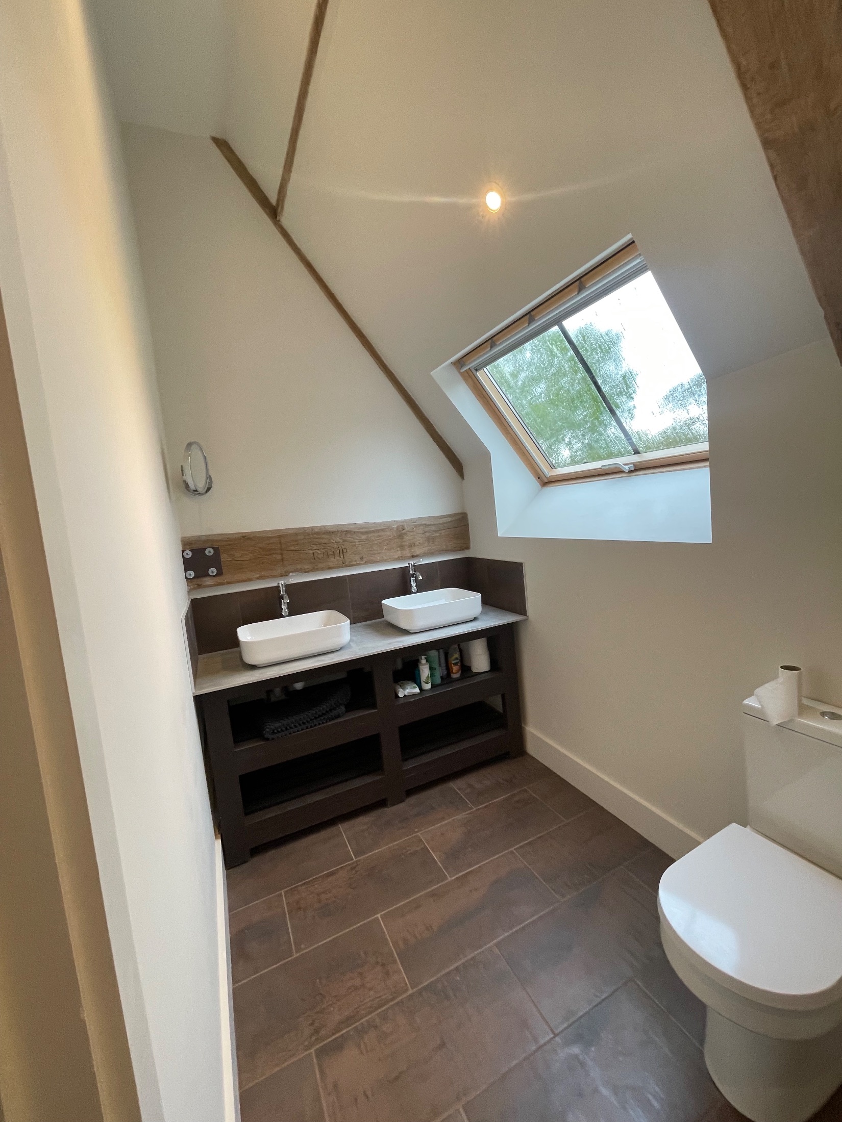 Barn conversion bedroom with exposed oak trusses and brick gable wall