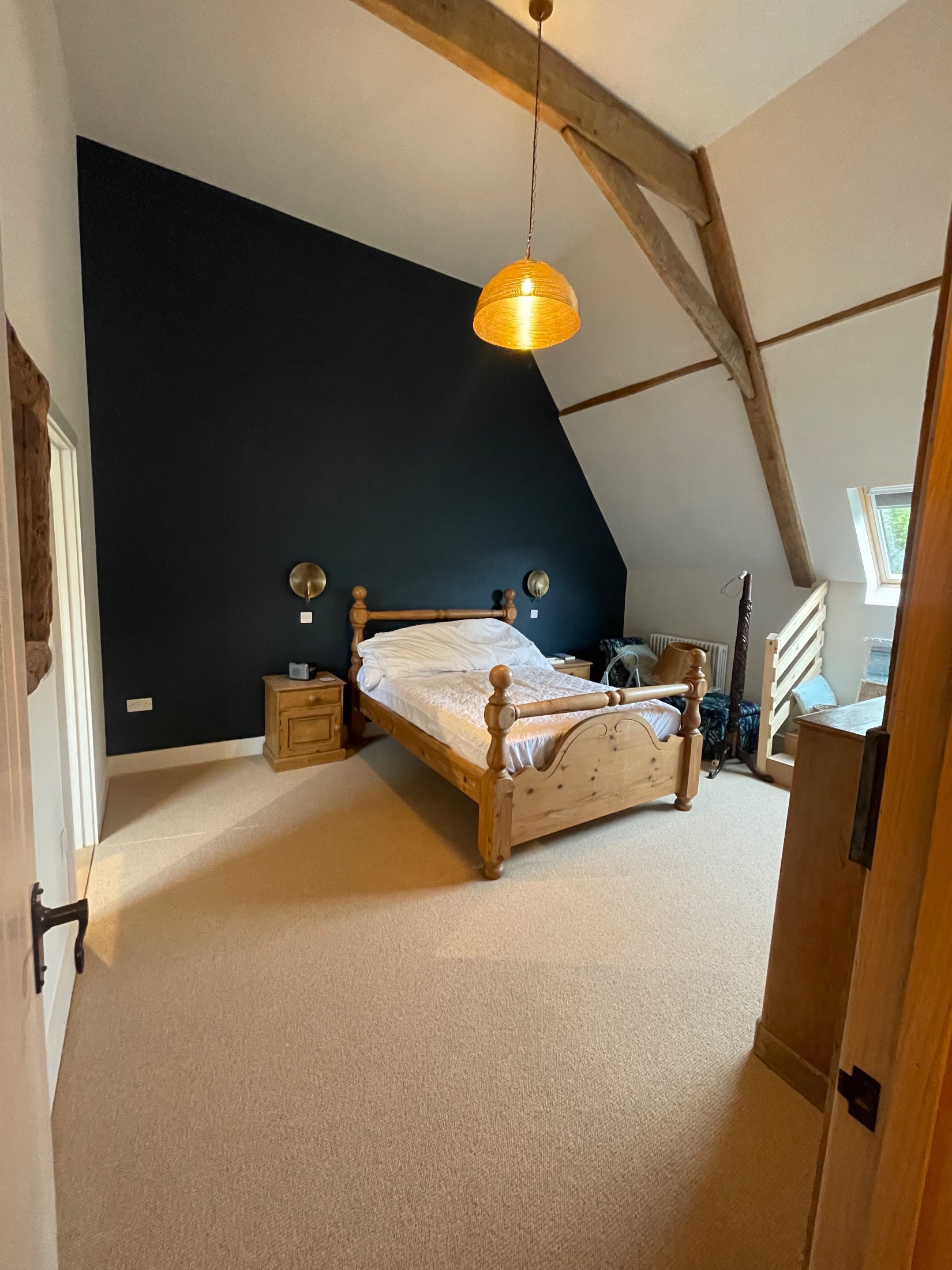 Barn conversion bedroom with exposed oak trusses and brick gable wall